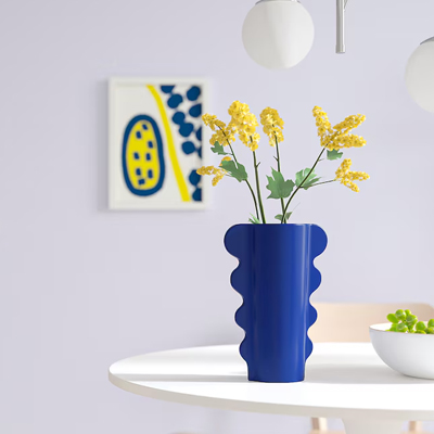 Donkerblauwe vaas in speels ontwerp, gevuld met gele bloemen.