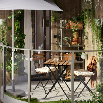Een klein balkon met een houten tuinset en veel groene planten