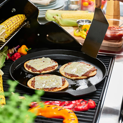 Drie kleine pizza's op een barbecuepan.