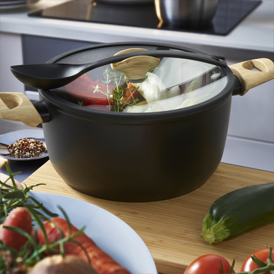 Grote, zwarte kookpan met deksel, gevuld met eten in de keuken.