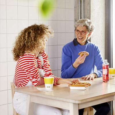 Twee vrouwen eten hotdogs in IKEA.
