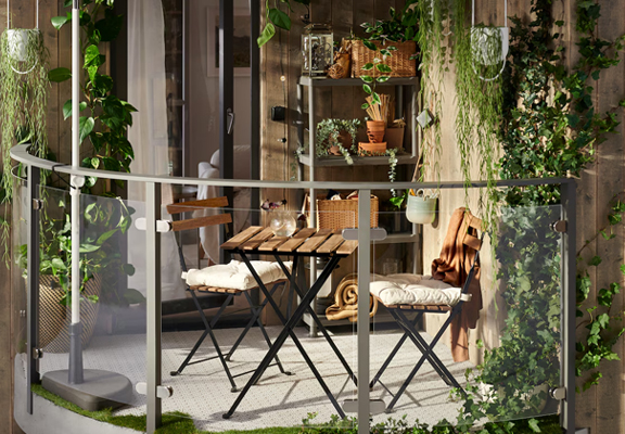 Een klein balkon met een houten tuinset en veel groene planten