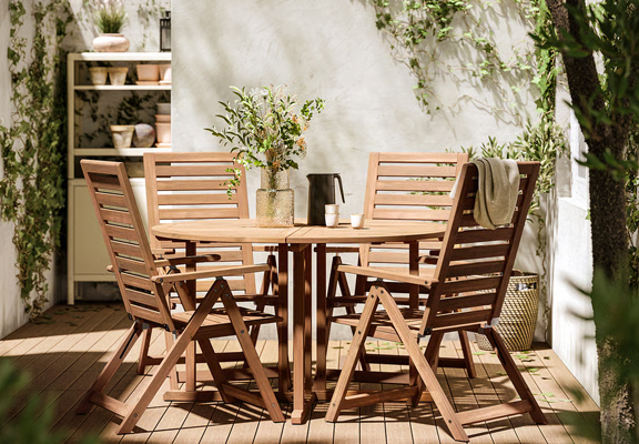 Ronde, houten buitentafel met vier stoelen.
