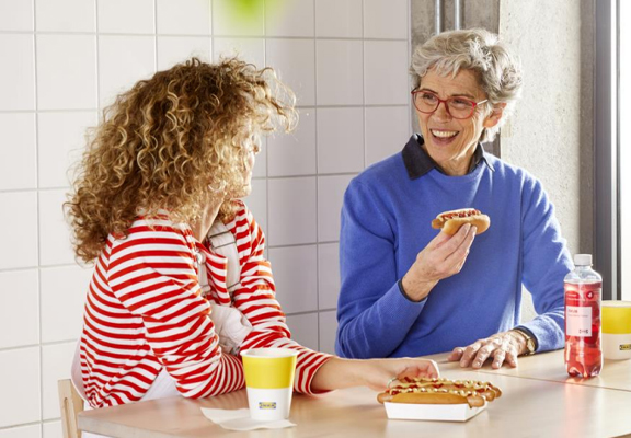 Twee vrouwen eten hotdogs in IKEA.