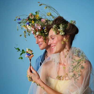 Man en vrouw met bloemen in hun haar en handen.