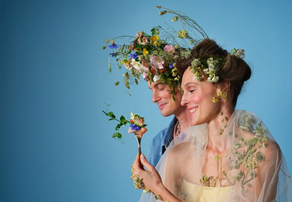 Man en vrouw met bloemen in hun haar en handen.