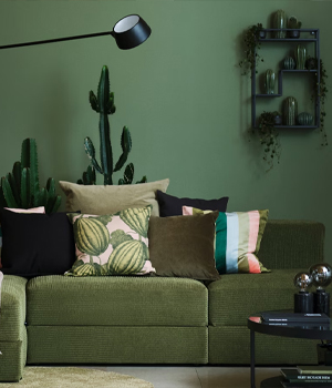 Grote, groene bank voor een groene muur met een zwarte salontafel en groene accessoires