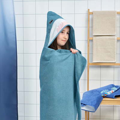 Meisje staat in de badkamer met een handdoek met capuchon.